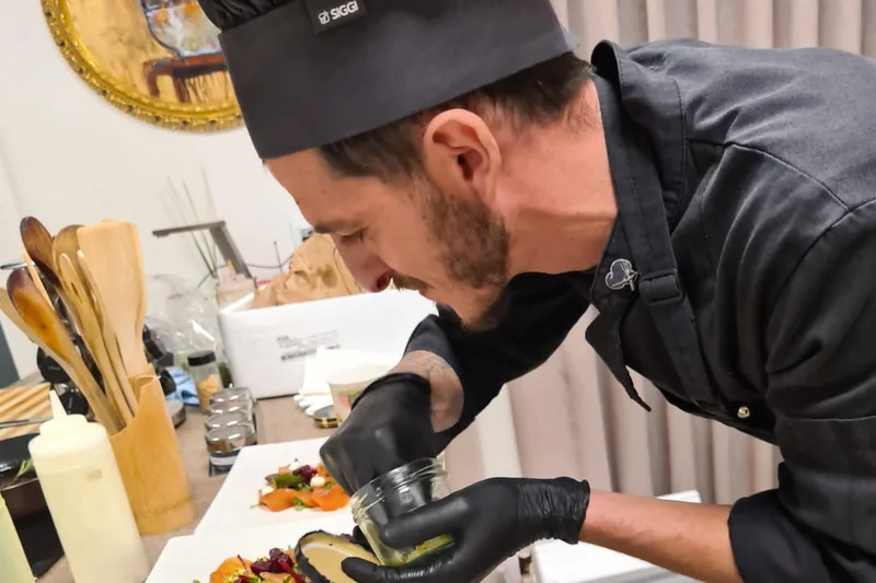 Marco Genna finishing a row of plates of salmon with beetroot, pistachio and rocket